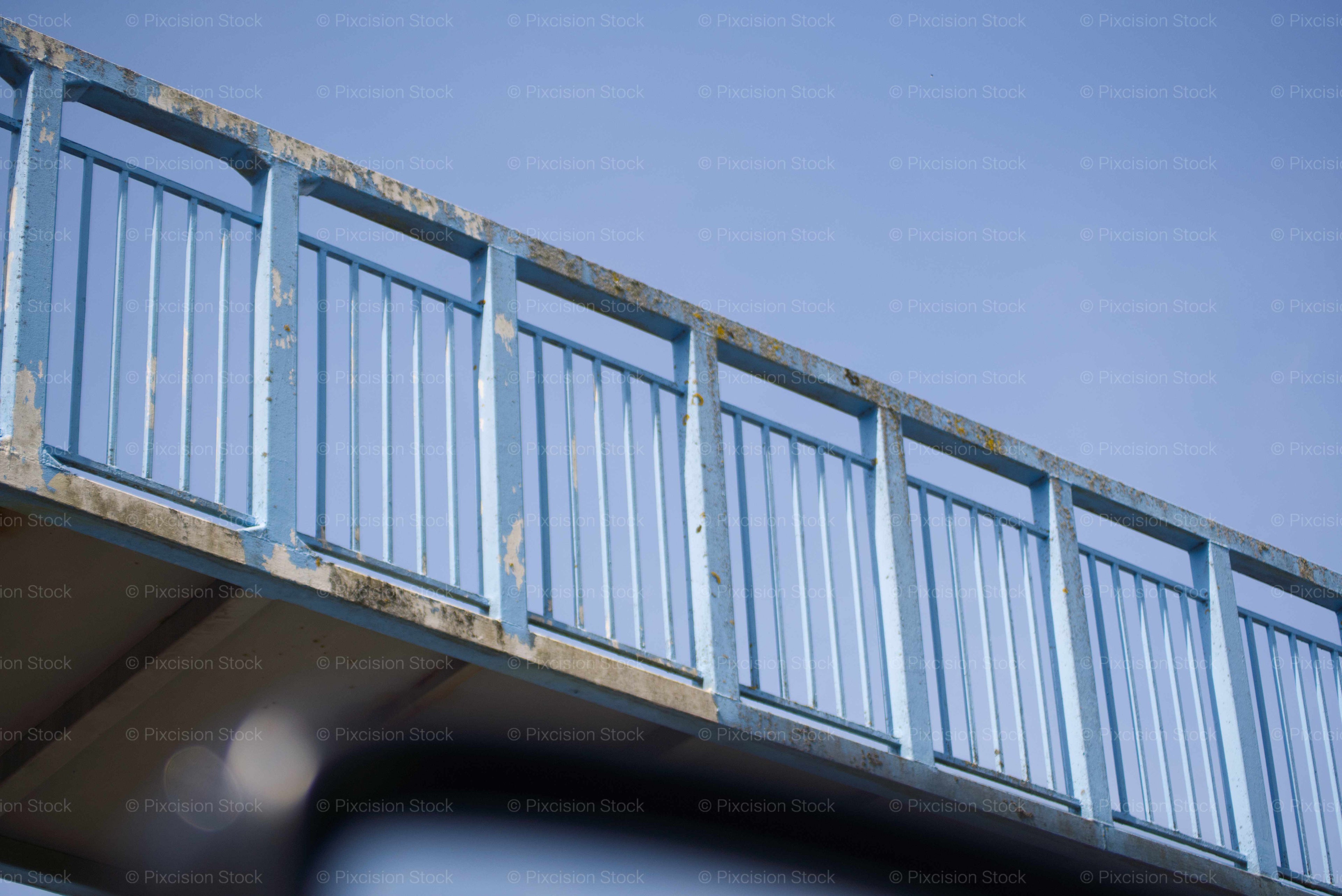 Metal railing on a bridge against a clear blue sky