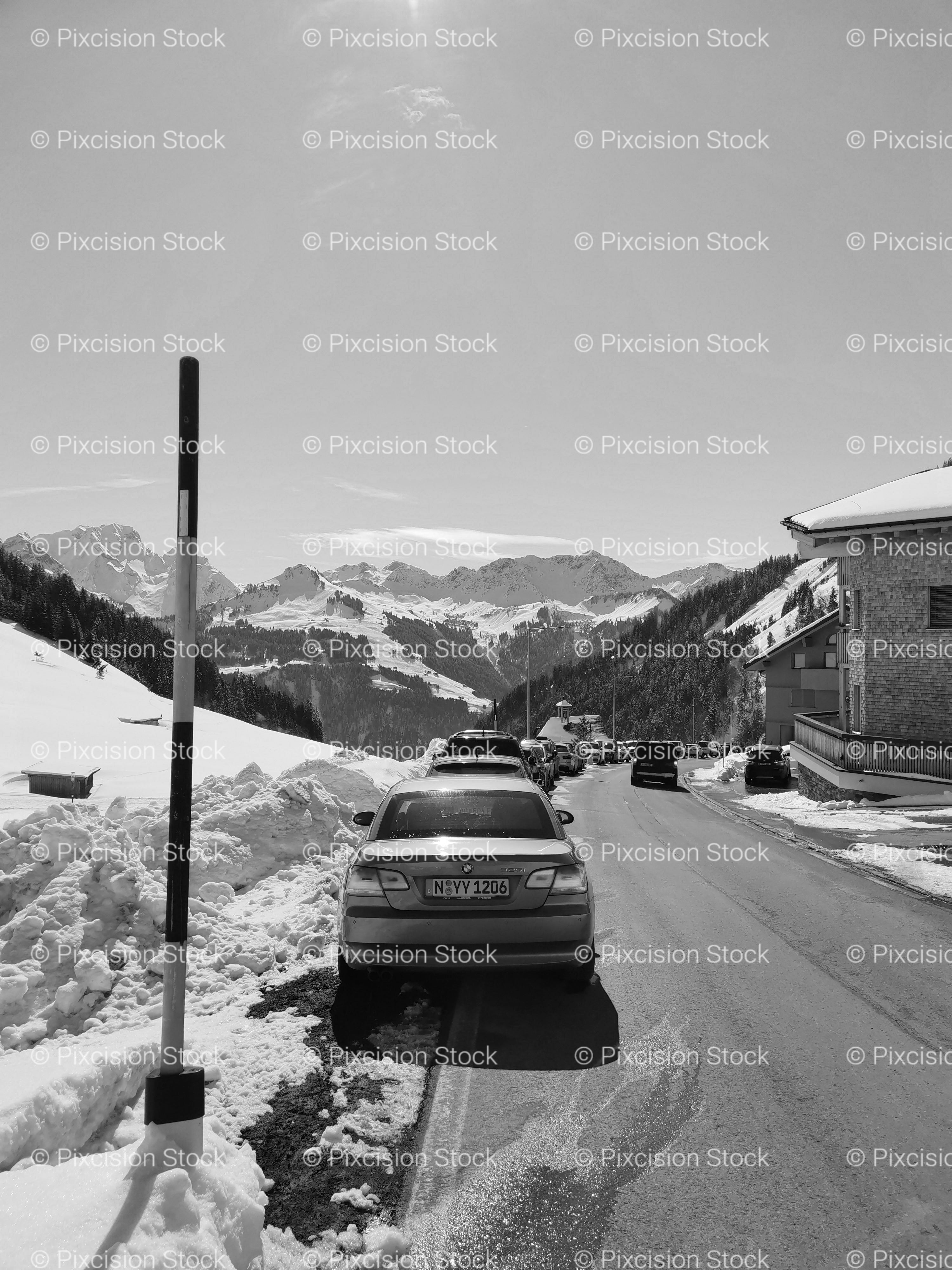 Cars Parked Along a Snowy Mountain Road Bordered by Marker Posts (Monochrome)