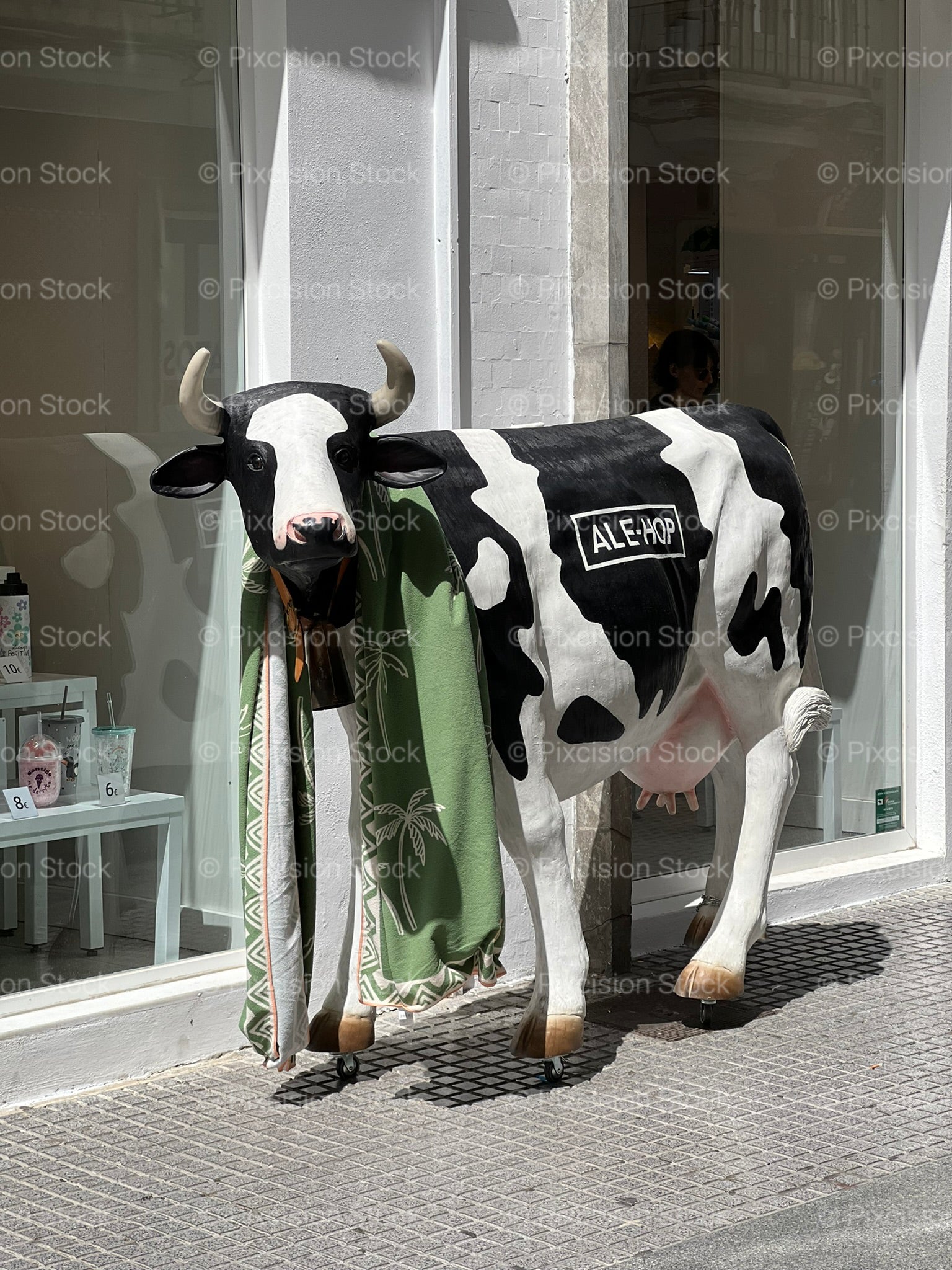 Life-Size Painted Cow Sculpture Outside a Spanish Retail Shop on a Sunny Street