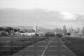 Paved Country Road Leading Toward a Distant Village Church (Monochrome)