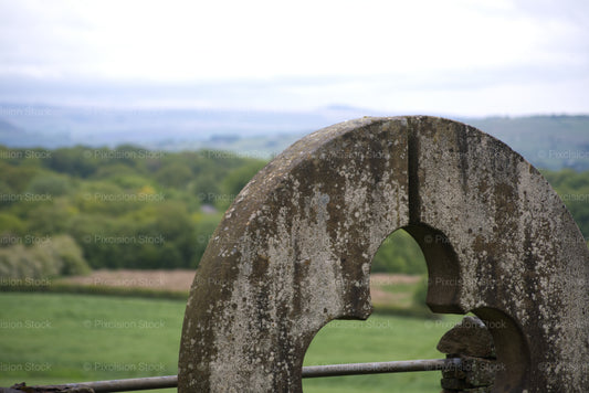 Stone millstone with a scenic landscape in the background