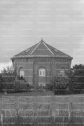 Octagonal Historic Brick Building Viewed Beyond a Boundary Fence (Monochrome)