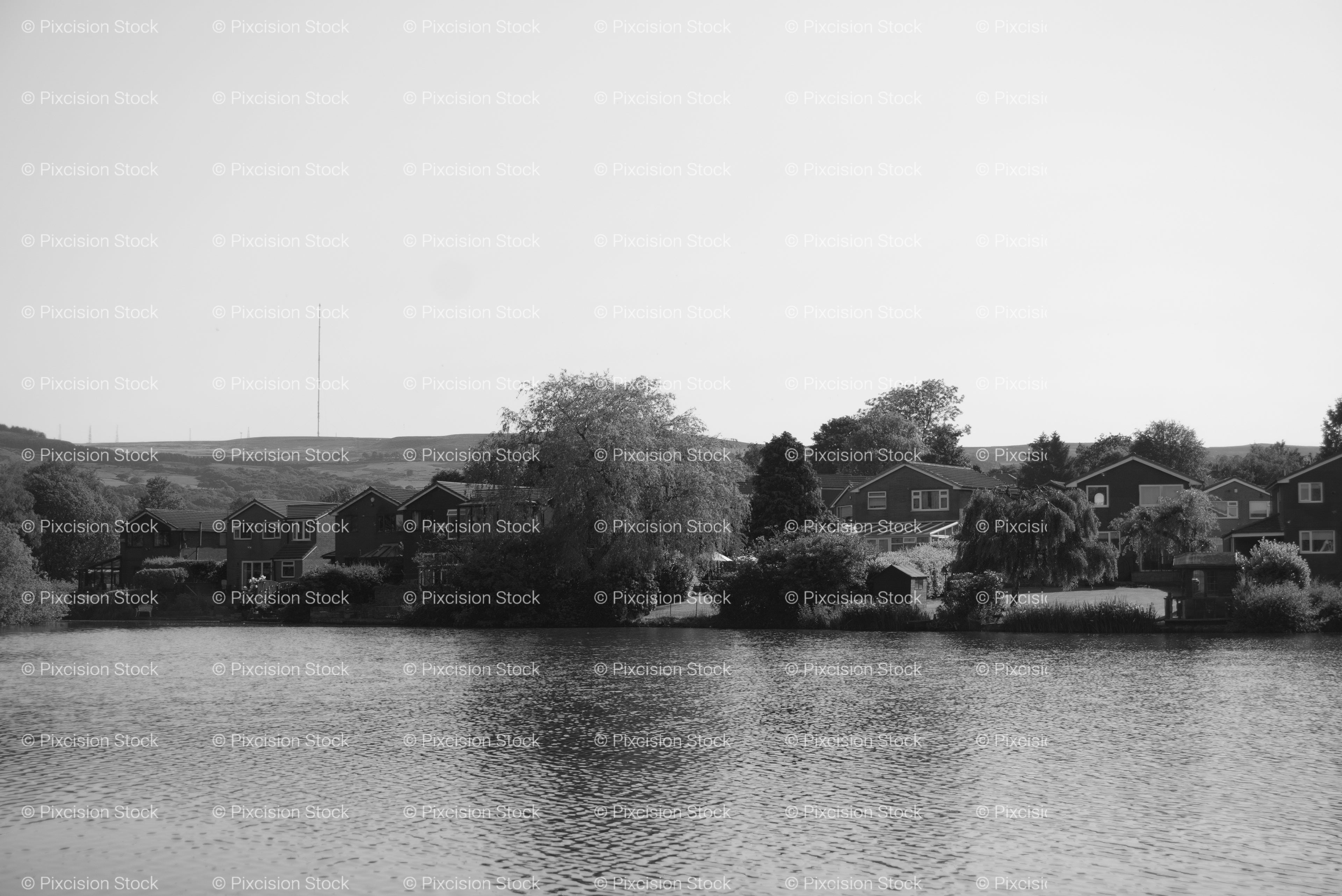 Calm River Scene Flanked by Trees and Small Buildings (Monochrome)