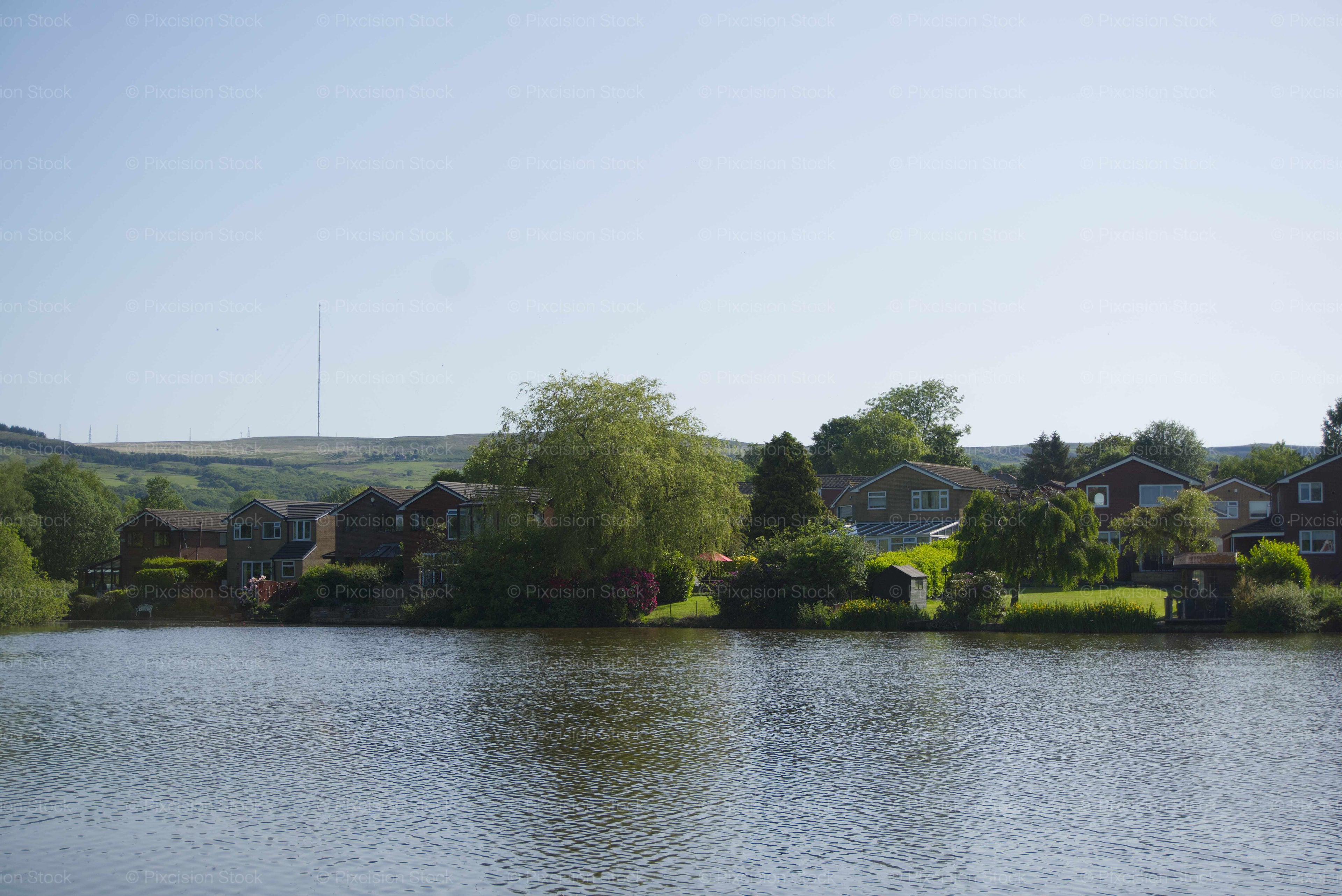 Calm Lake Scene Flanked by Trees and Small Buildings