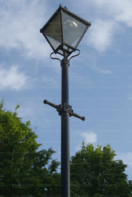 Traditional street lamp against a blue sky with trees in the background
