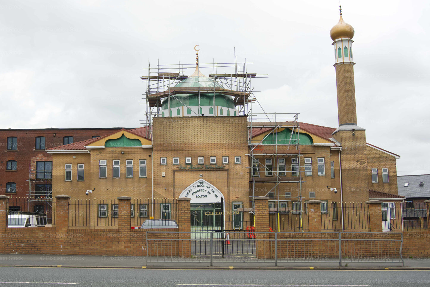 Large brick building with a minaret and scaffolding, under construction or repair.