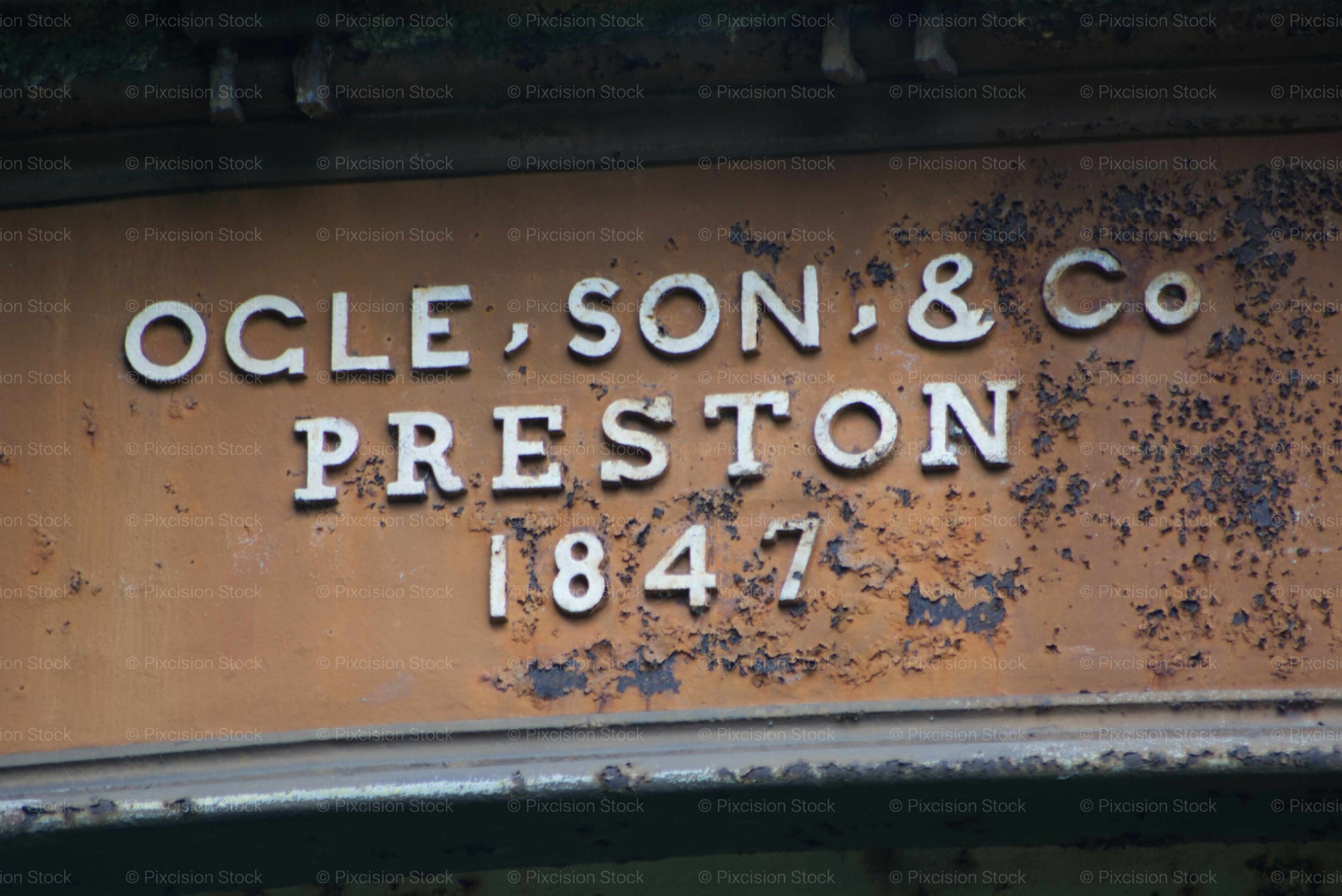Rust-covered metal plate with 'Ogle, Son & Co Preston 1847' text