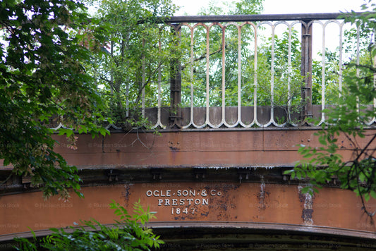 Old railway bridge with 'Ocle & Son & Co Preston 1847' branding, surrounded by greenery.