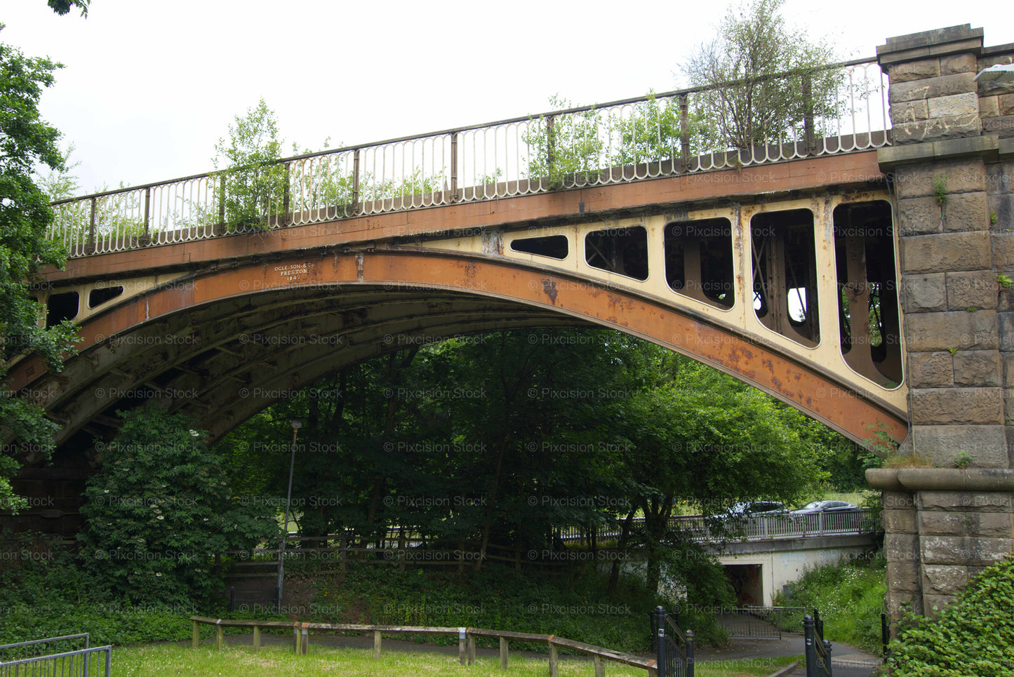 Stone bridge with metal railing over a green landscape
