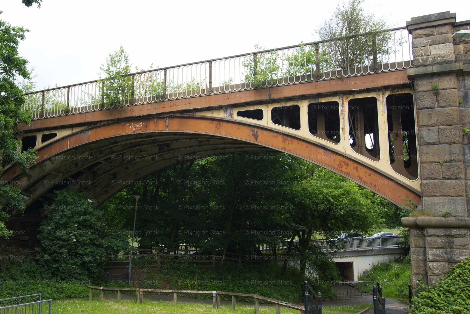 Stone bridge with metal railing over a green landscape