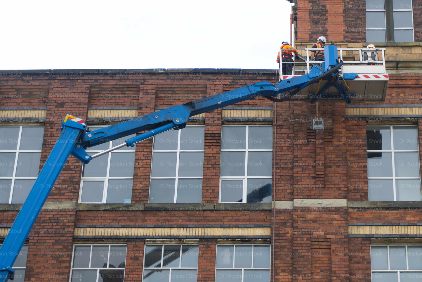 Blue cherry picker with workers on a brick building