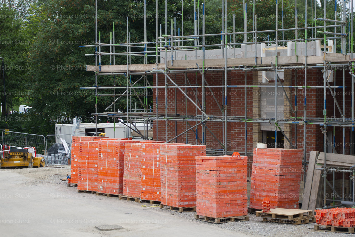 Scaffolding erected around a new brick building under construction with stacked supplies