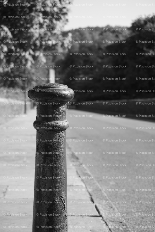 Vertical Shot of a Metal Bollard or Post Along a Paved Path
