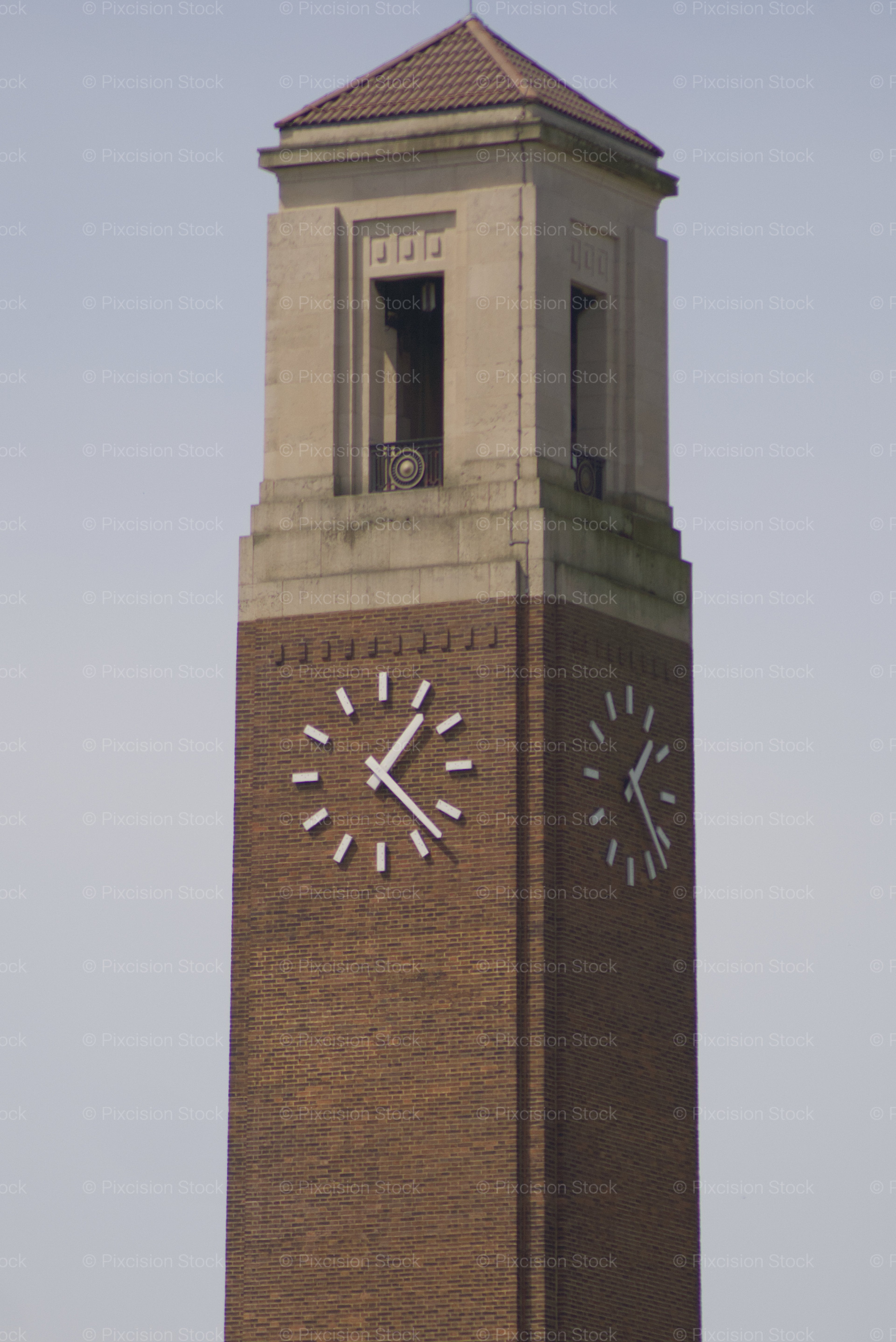 Brick clock tower with a pointed roof against a clear sky