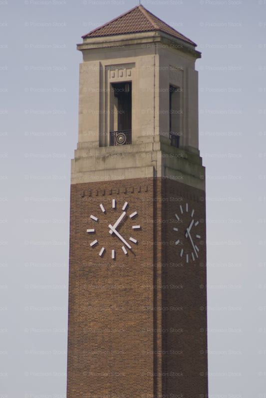 Brick clock tower with a pointed roof against a clear sky