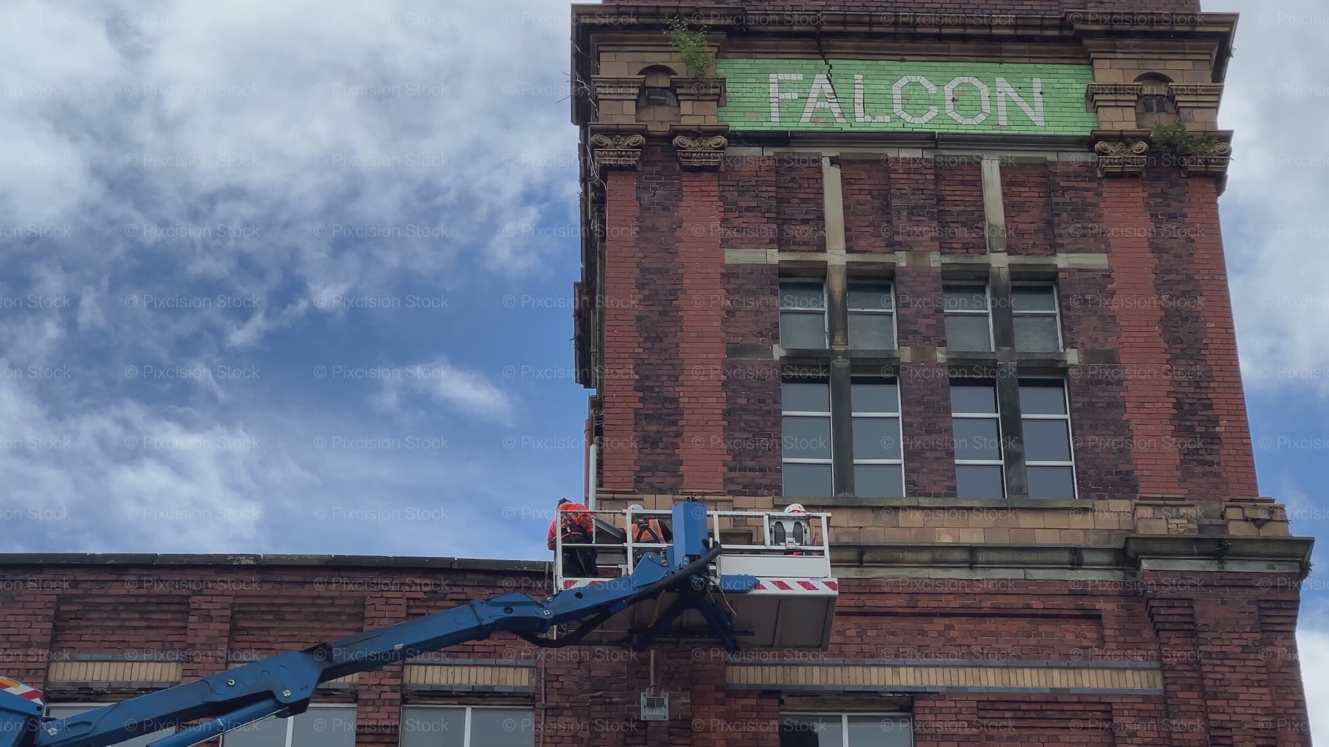 A video showing workers in a cherry picker lift inspecting the historic brick tower of Falcon Mill.